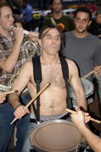 A shirtless white man plays a snare drum at Zuccotti Park, 2011