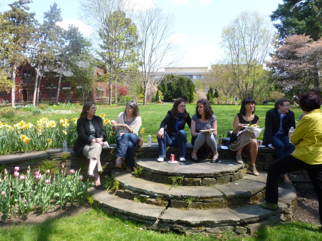 7 people sit on stone steps talking on a spring day, surrounded by tulips and daffodils From Left: Renate Ferro, Ladi Dell'aira, Sarah Ensor, Jeanette Jouili, Nina Sun Eidsheim, Brian Hanrahan, and Norie Neumark, Image by JS