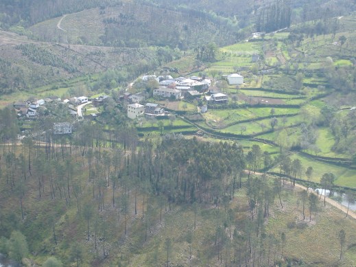 Aerial view of Nodar Portugal, a small town amidst rolling green hills and trees. 