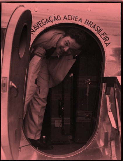 red-tinted image of Orson Welles about to step off a plane labeled "Navegacão Aeres Brasiliera"