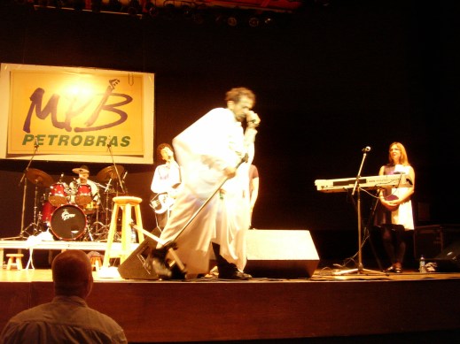 Tom Zé in 2008 performing in front of a Petrobras sign, photo used by CC license, Neto Silveira