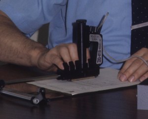 Lauer's fingers are pictured in the finger-rests of the Visotactor, scanning a document.