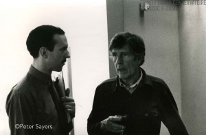 "Photograph of John Cage talking to another guest at a drinks reception at the Cage/Cunningham Residency at the Laban Centre, Laurie Grove, London, July 1980" by Flickr user Laban Archive,