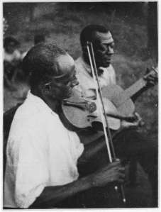 Stavin' Chain playing guitar and singing the ballad "Batson" accompanied by a musician on violin, Lafayette, La.